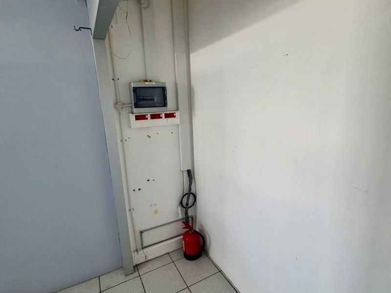 A utility corner featuring an electrical distribution board and ceramic tiled flooring, suitable for maintenance or storage purposes.