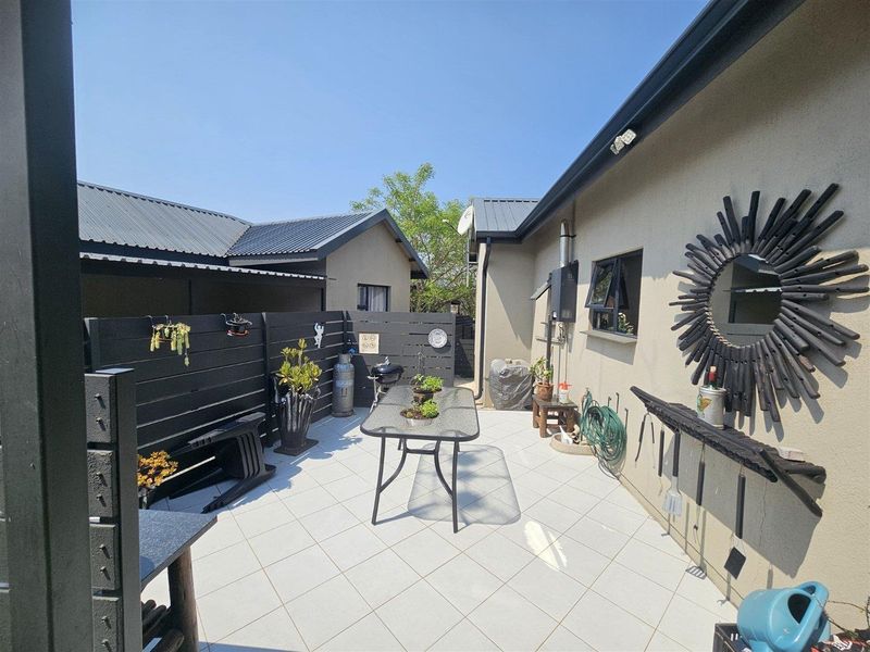 A paved outdoor patio area featuring a timber privacy screen, tiled flooring, and direct access to the main building structure.