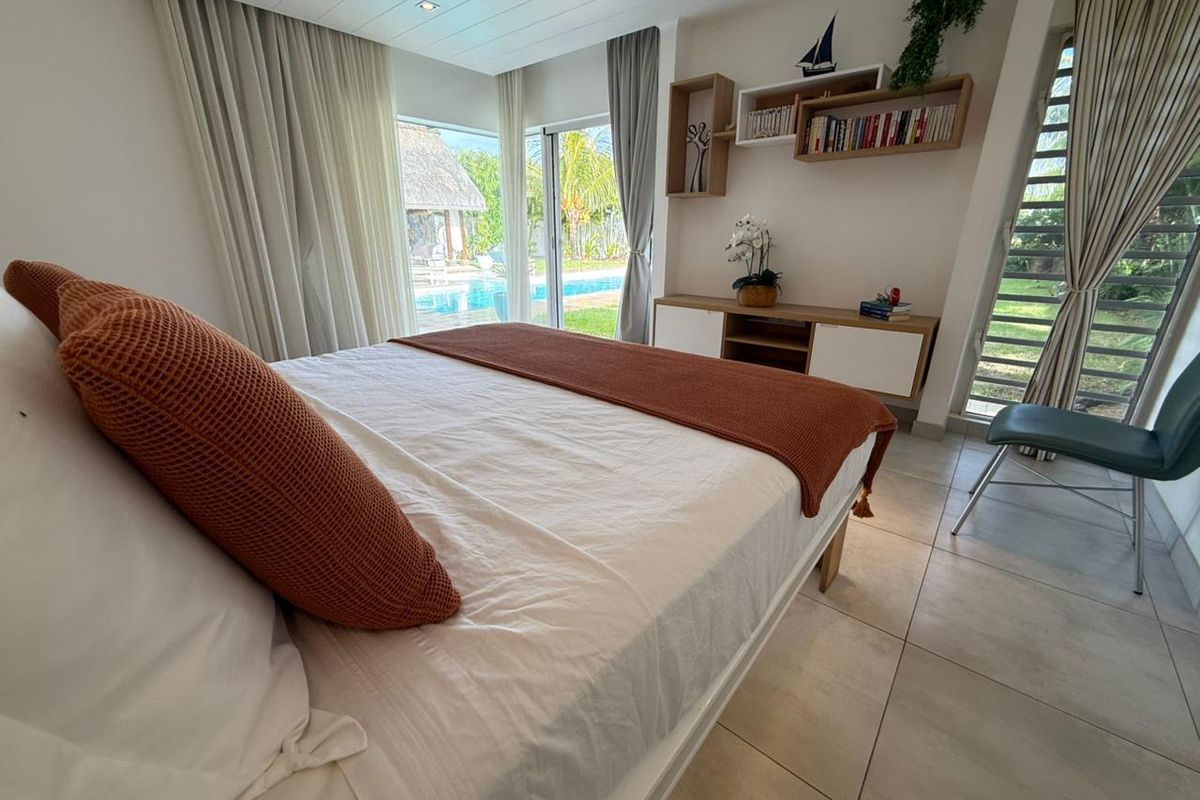 Bright bedroom featuring large sliding glass doors with direct access to the pool area, tiled flooring, and built-in shelving.