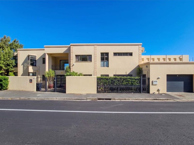 Front elevation of a modern two-story house featuring a secure boundary wall, electric fencing, wrought iron gate, and an integrated garage.