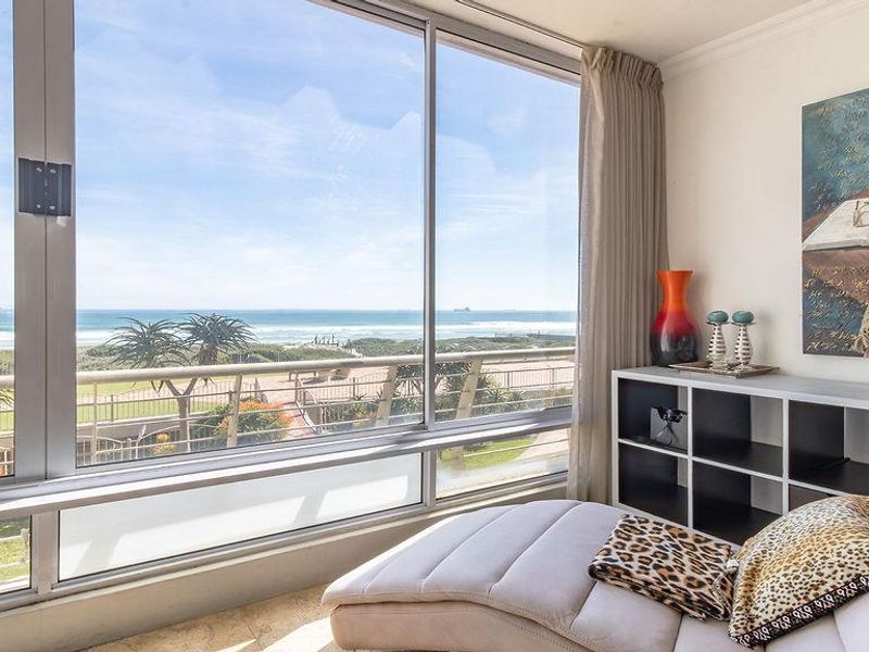 A bright living area featuring expansive floor-to-ceiling windows that offer panoramic ocean views and abundant natural light.