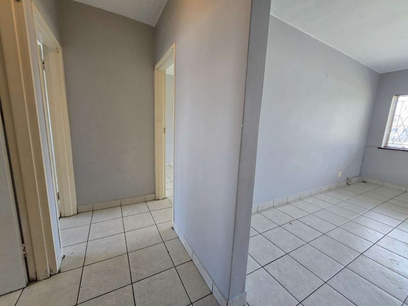 An empty hallway area featuring neutral wall paint and tiled flooring, providing access to adjacent rooms within the apartment.