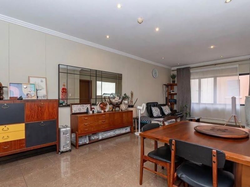 Spacious open-plan living and dining area featuring tiled flooring, recessed downlighting, and decorative wall molding, offering a versatile layout for modern living.