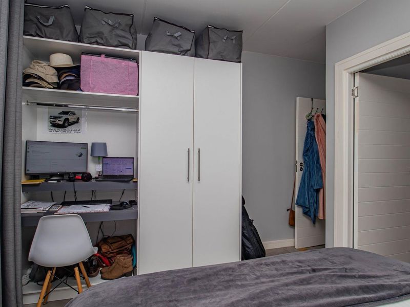A bedroom featuring built-in white cabinetry and an integrated desk workspace, providing efficient storage and study solutions within the room.