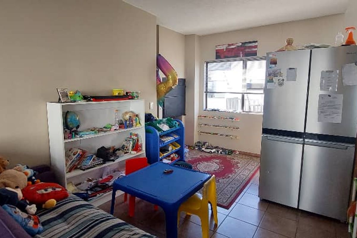 A multi-purpose living area featuring tiled flooring and a large window, currently utilized as a play and storage space.