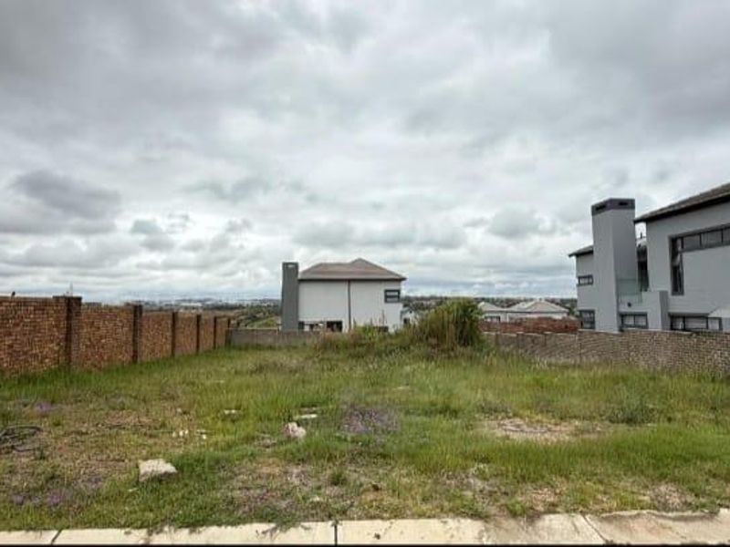 A vacant residential plot featuring established brick boundary walls and surrounding neighborhood views, ready for new construction.