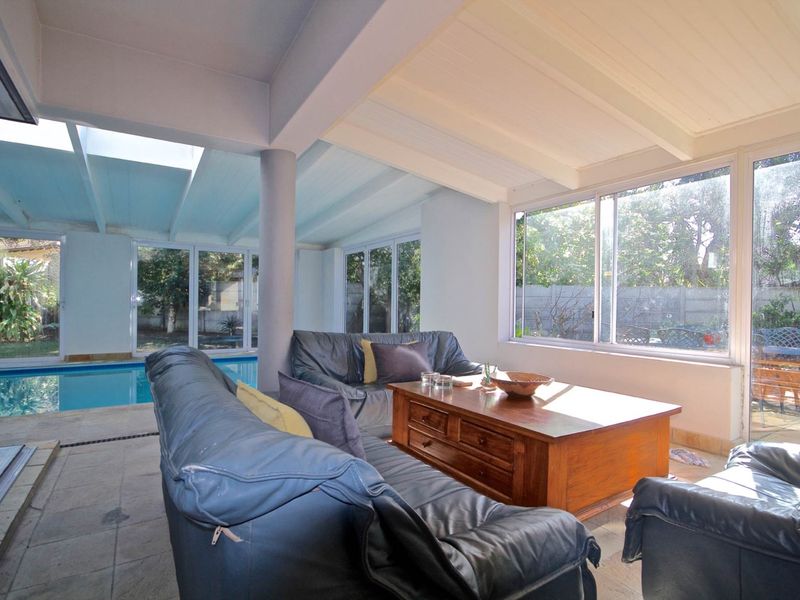 Spacious enclosed patio area featuring tiled flooring, exposed beam ceilings, and direct access to an indoor swimming pool through large sliding glass doors.