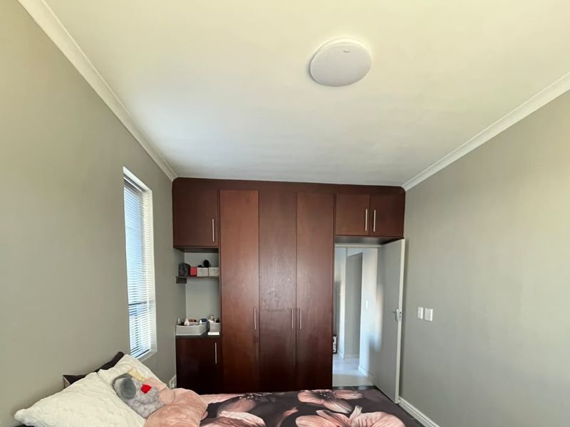 A well-maintained bedroom featuring dark wood built-in cupboards, neutral wall tones, and a flush mount ceiling light.