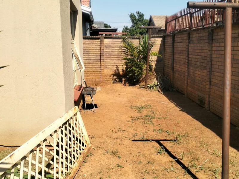 A rear exterior space featuring a brick boundary wall, metal washing line, and an open yard area with potential for landscaping.