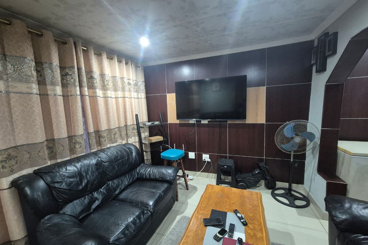 A living room featuring tiled flooring and dark wood-look wall paneling, providing a functional space for relaxation.