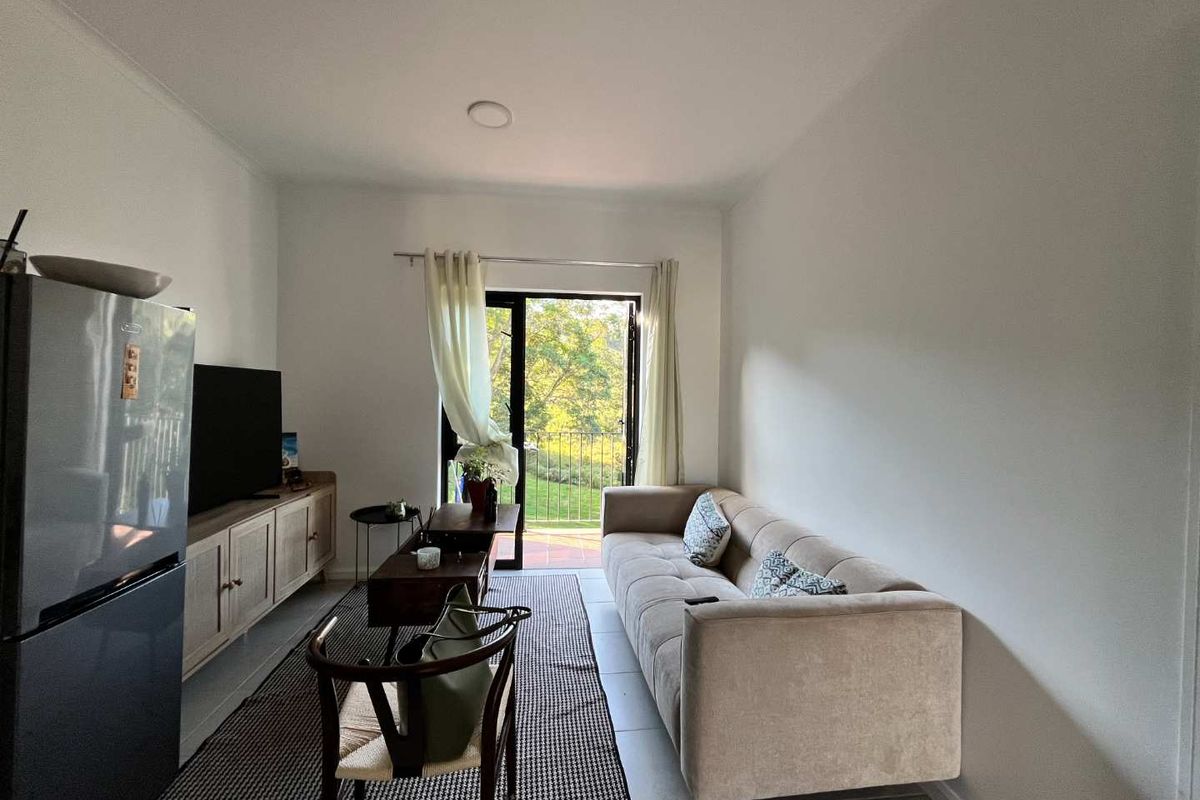 A bright living room featuring tiled flooring and a sliding glass door that opens to an outdoor balcony area.