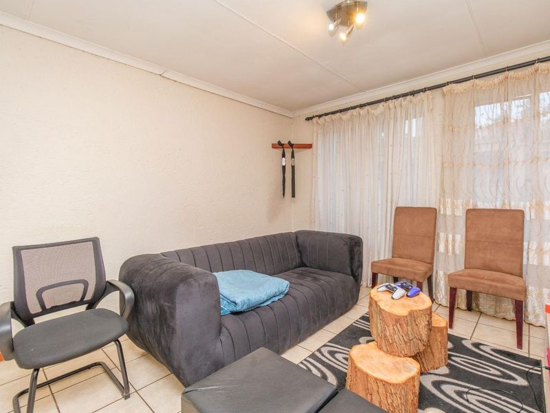 A living room area featuring tiled flooring and curtain rails, requiring cosmetic updates to improve the overall aesthetic and condition of the space.