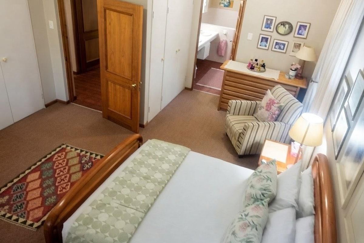 A carpeted bedroom featuring built-in cupboards and direct access to an en-suite bathroom.