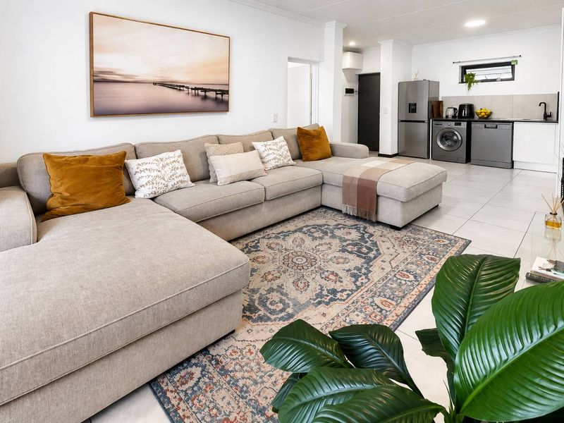 Modern open-plan living area featuring tiled floors, recessed lighting, and a functional kitchen space with integrated cabinetry and sink.