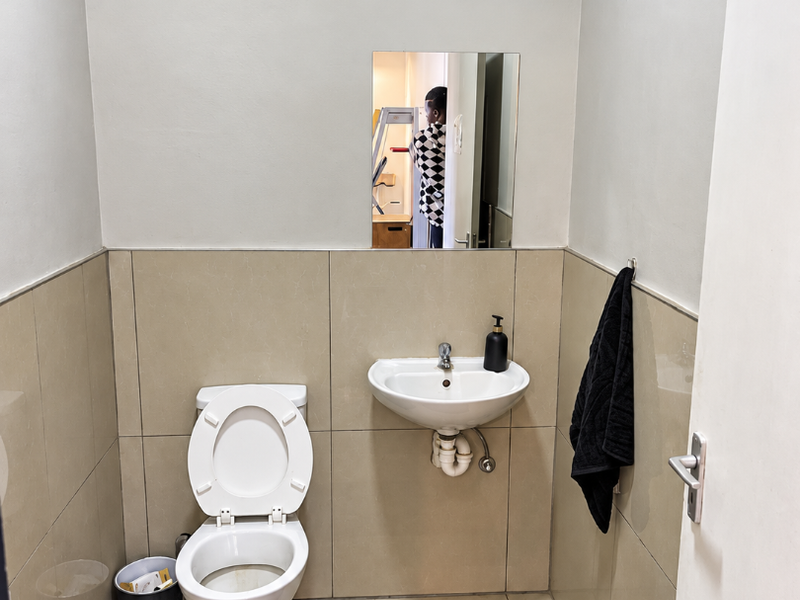 A clean, functional guest bathroom featuring a wall-mounted basin, toilet, and neutral tiled finishes.
