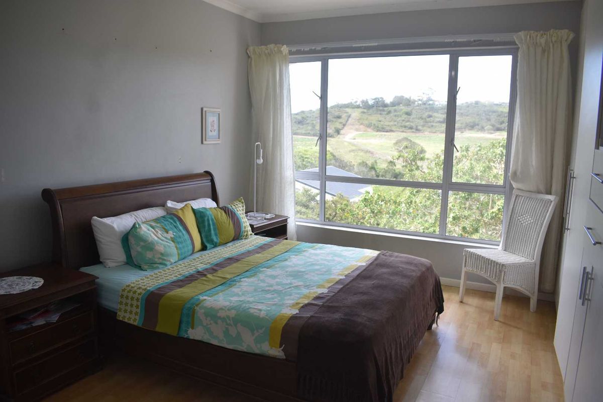 A bright bedroom featuring large windows with scenic views, laminate flooring, and built-in cabinetry.
