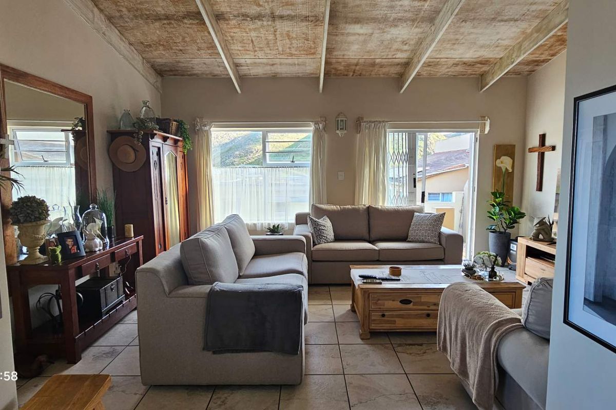 Spacious living room featuring exposed beam ceilings, tiled flooring, and direct access to the outdoor area through sliding glass doors.