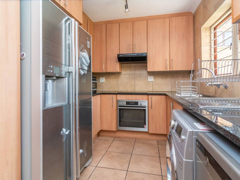 A functional kitchen featuring light wood-tone cabinetry, granite countertops, tiled backsplash, and built-in oven with extractor fan.