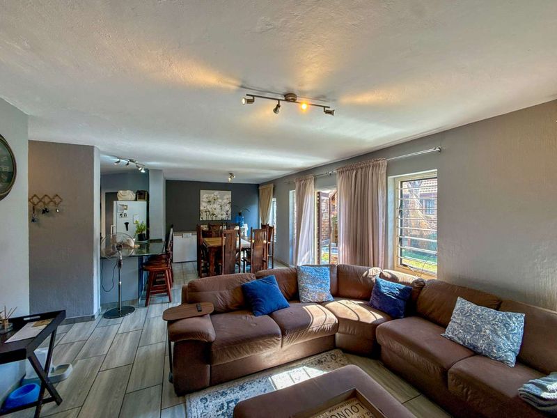 Open-plan living and dining area featuring tiled flooring, track lighting, and direct access to the outdoor space through sliding glass doors.