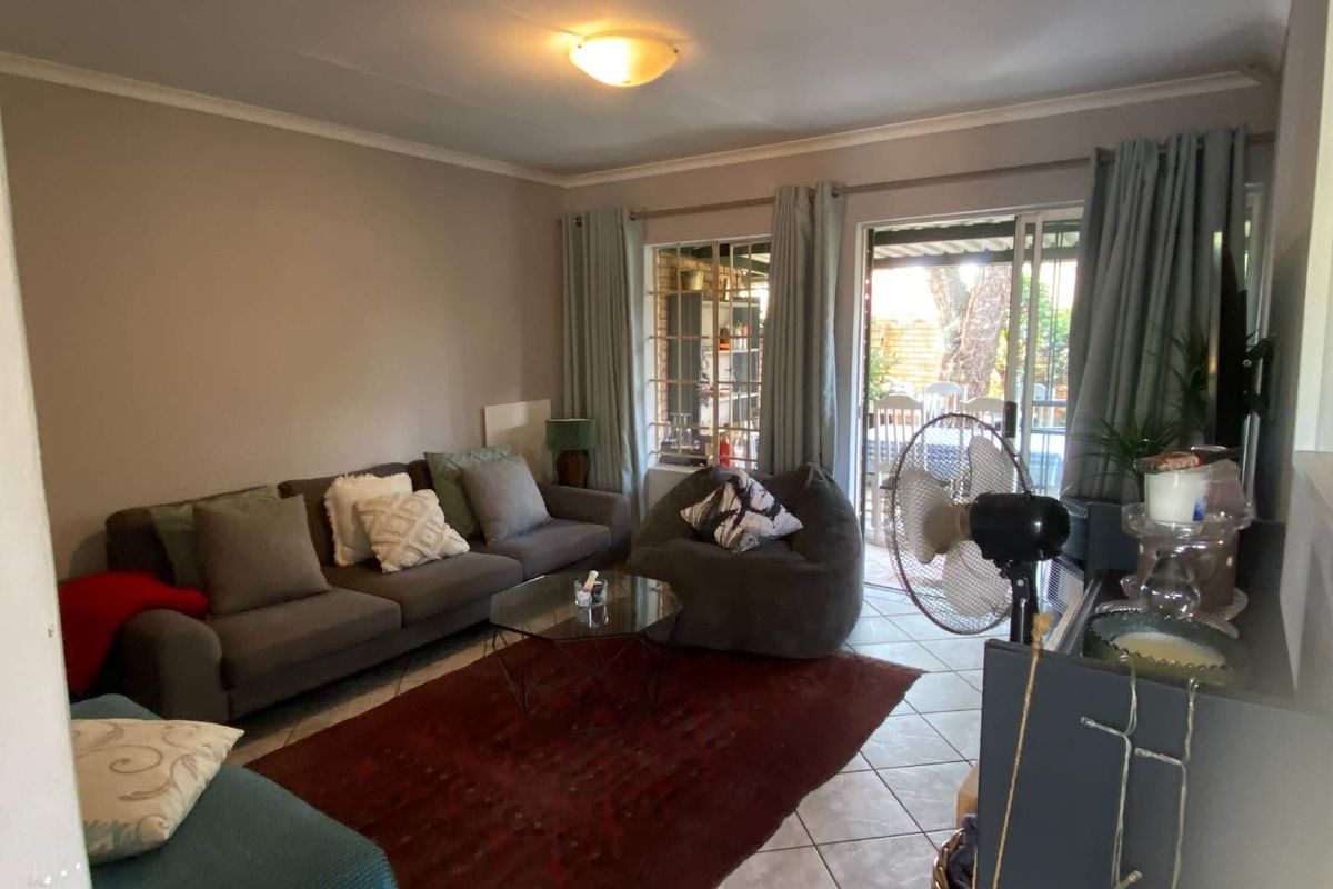 A comfortable living room featuring tiled flooring and large sliding glass doors that provide access to the outdoor patio area.
