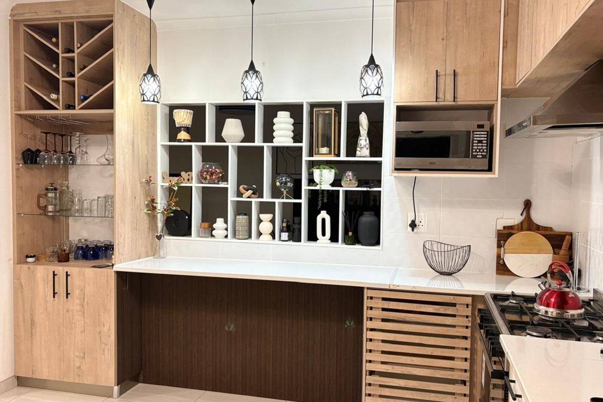 Modern kitchen featuring light wood cabinetry, integrated microwave, gas hob, stone countertops, and a decorative built-in display shelving unit.