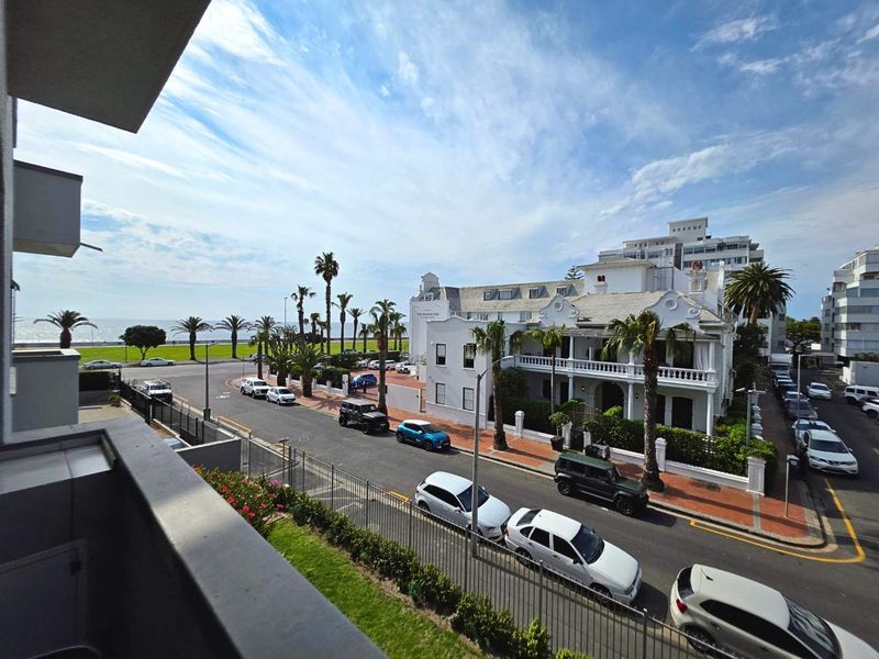 Elevated street and coastal view overlooking the neighbourhood, palm trees, and nearby historic architecture from a private balcony.