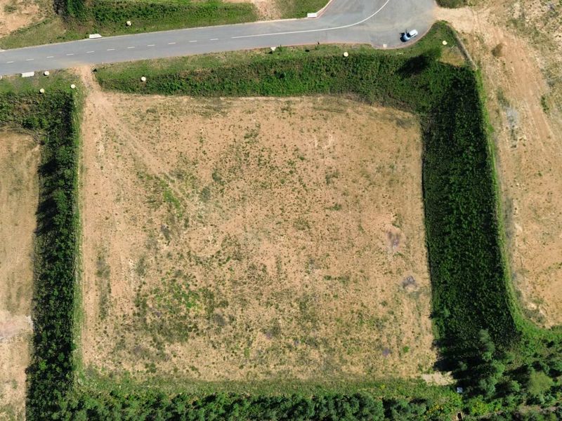 Aerial view of a vacant industrial plot featuring established hedgerow boundaries and direct access to a paved road.