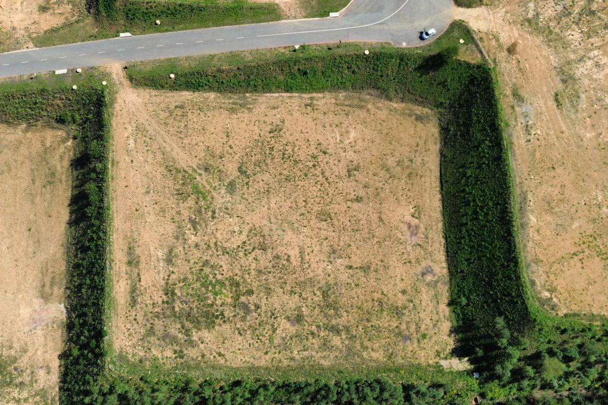 Aerial view of a vacant industrial plot featuring established hedgerow boundaries and direct access to a paved road.