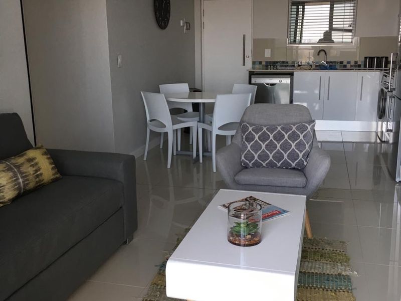 Open-plan living and kitchen area featuring modern tiled flooring, neutral wall tones, and a functional kitchen layout with integrated appliances.