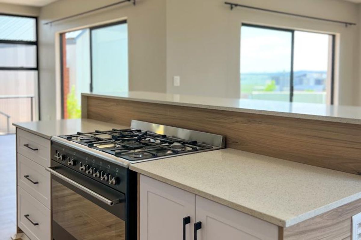 Modern kitchen island featuring a built-in gas cooktop, oven, stone countertops, and contemporary cabinetry with integrated lighting.
