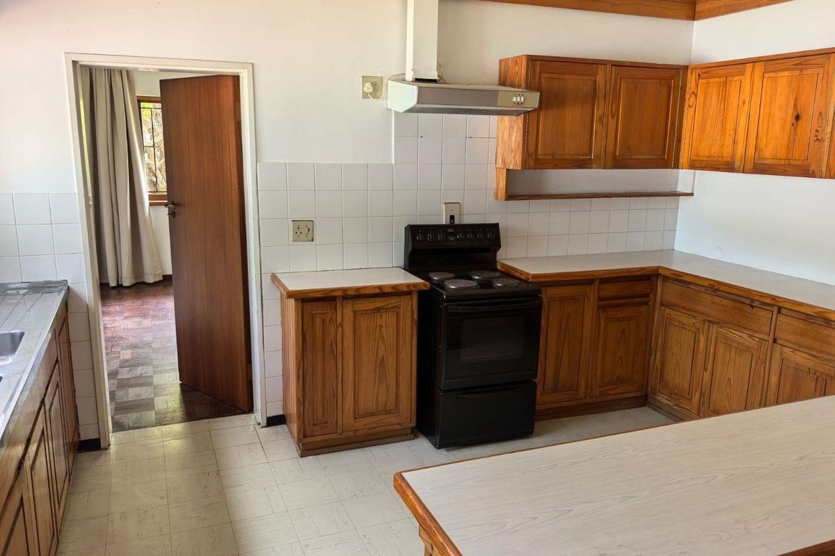 A functional kitchen featuring wooden cabinetry, a built-in extractor fan, and a freestanding stove, offering a classic layout with potential for modern updates.