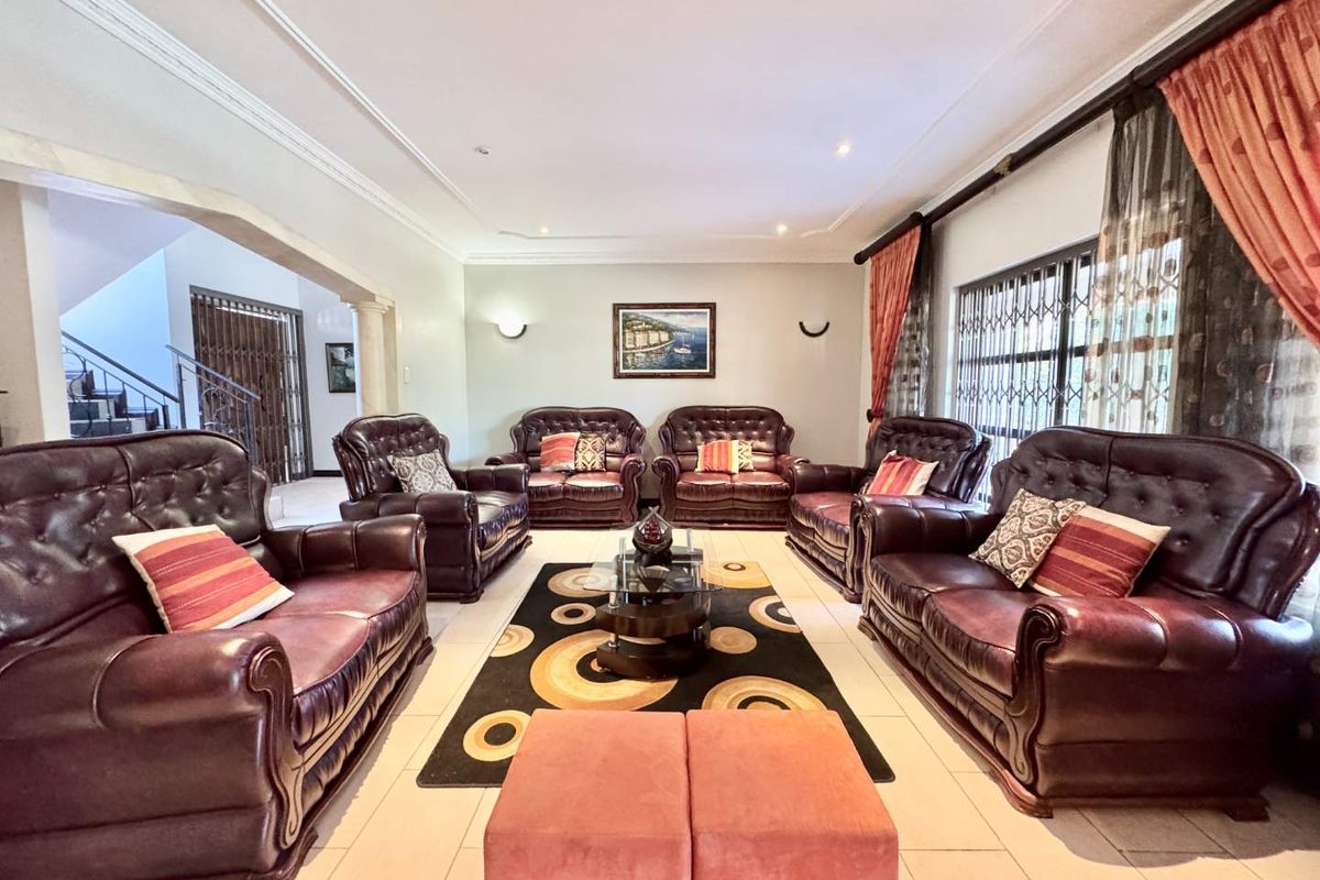 Spacious living room featuring tiled flooring, decorative ceiling cornices, and recessed lighting, with an open-plan layout leading to the staircase area.