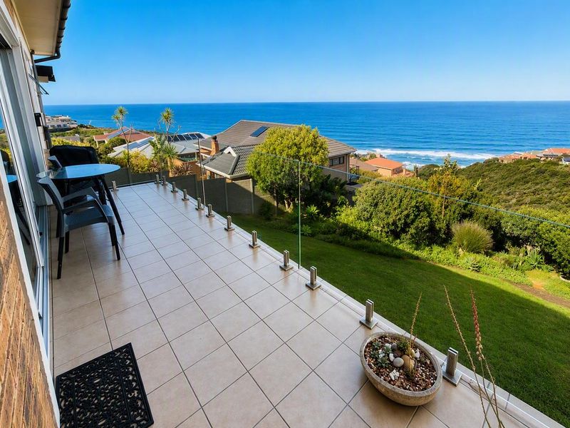 Spacious balcony featuring tiled flooring and a modern frameless glass balustrade, offering expansive ocean and coastal views.