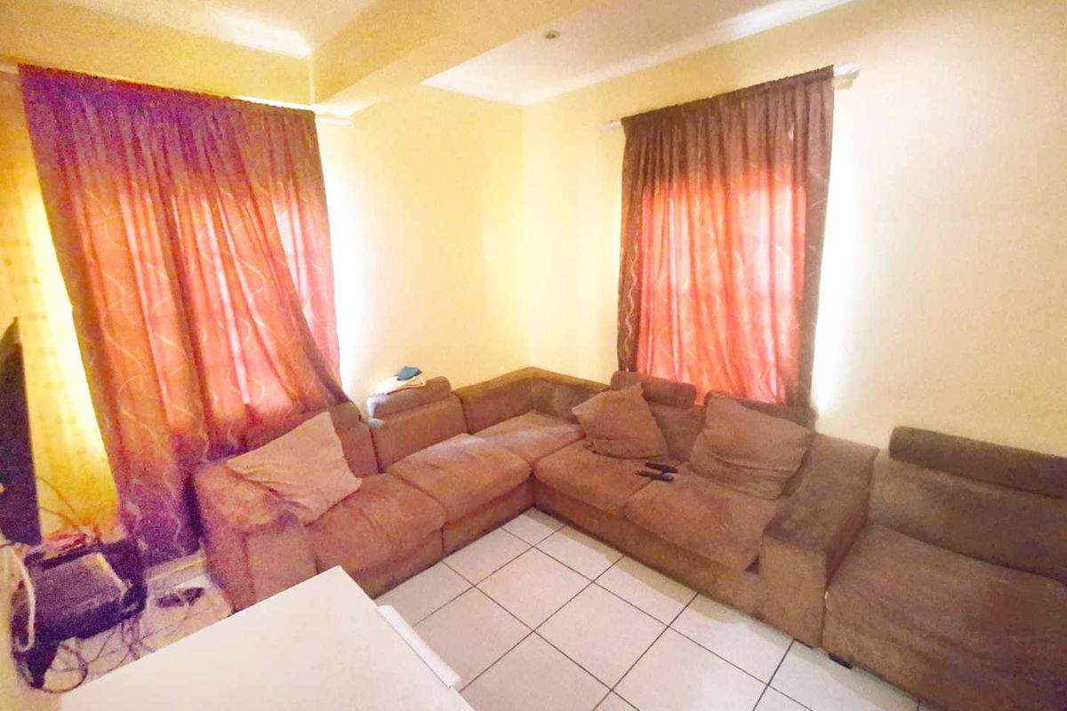 A living room area featuring tiled flooring and cove ceiling details, providing a functional space for relaxation.