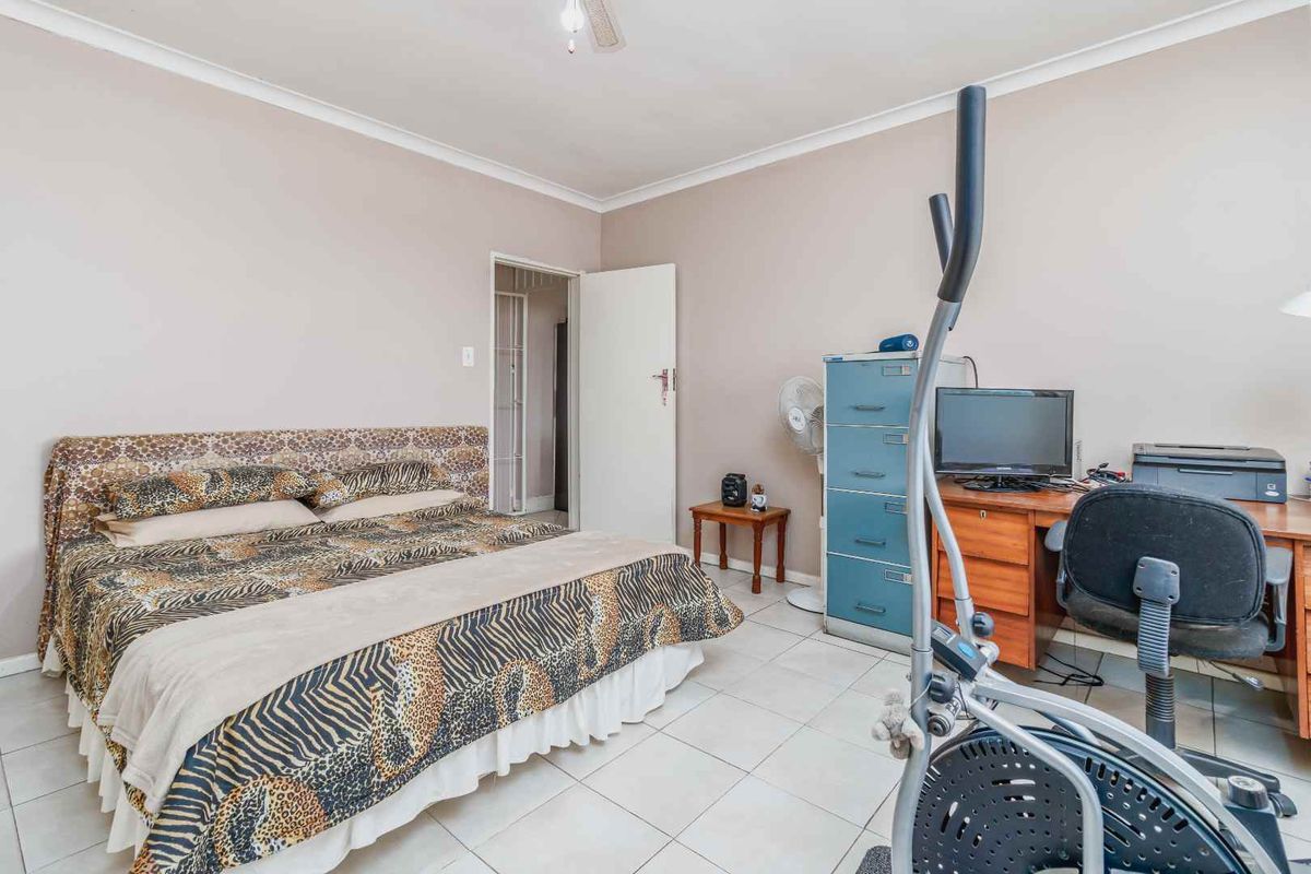 A functional bedroom featuring tiled flooring and neutral wall finishes, providing a versatile space for rest or home office use.