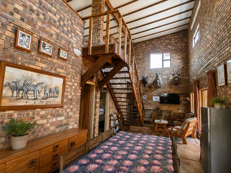 Spacious open-plan living and dining area featuring high vaulted ceilings with exposed timber beams and distinctive face-brick walls throughout.