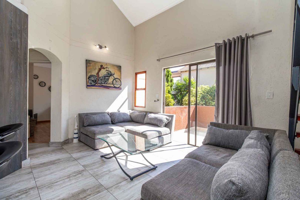Spacious living room featuring a high vaulted ceiling, tiled flooring, and a sliding glass door providing access to an outdoor balcony area.