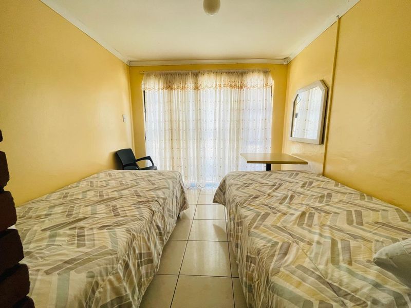 A bedroom featuring tiled flooring and a sliding glass door with curtains, providing access to natural light.