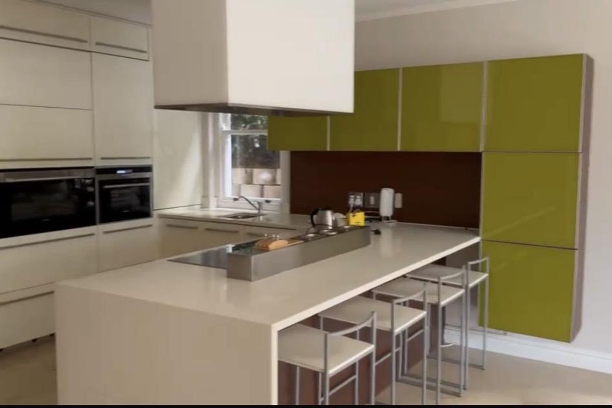 Modern kitchen featuring a large island with integrated cooktop, high-gloss cabinetry in white and lime green, and built-in wall ovens.