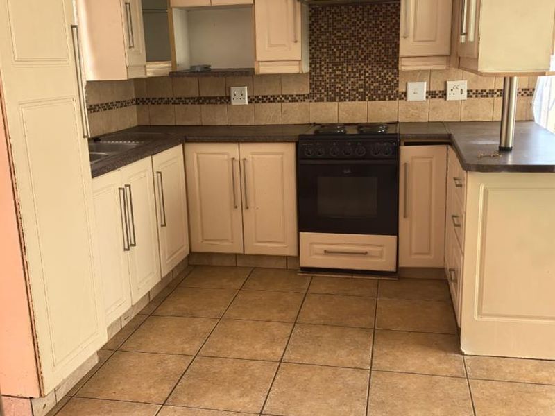 A functional kitchen featuring built-in cabinetry, a tiled backsplash, and integrated oven and hob, offering a practical layout ready for updates.