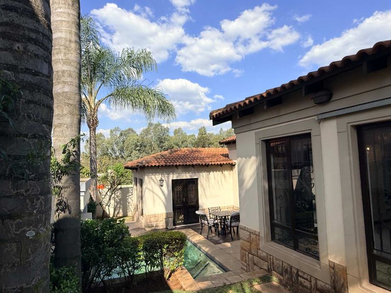 A well-maintained rear exterior view featuring a swimming pool, paved patio area, and classic terracotta roof tiles with stone-clad wall finishes.