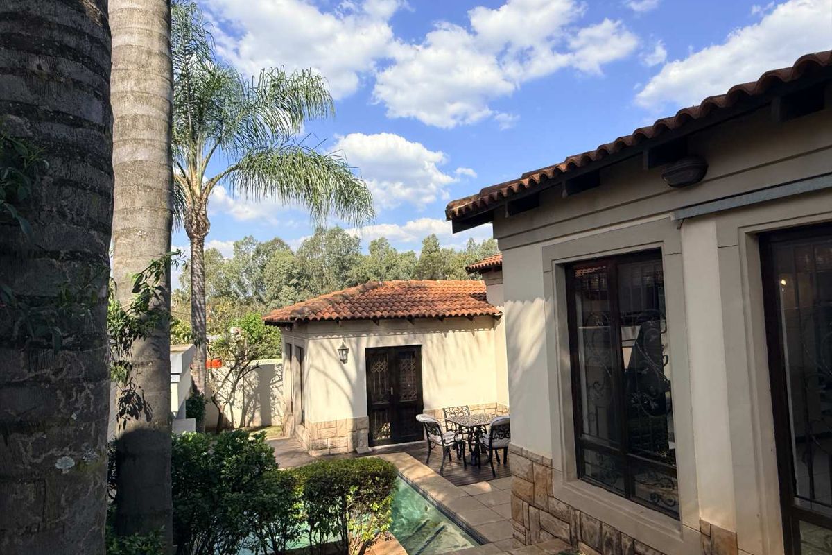 A well-maintained rear exterior view featuring a swimming pool, paved patio area, and classic terracotta roof tiles with stone-clad wall finishes.