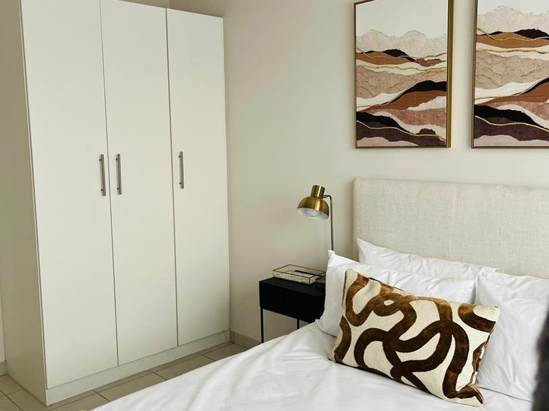 A well-maintained bedroom featuring a built-in wardrobe and neutral tiled flooring, offering a clean and functional living space.