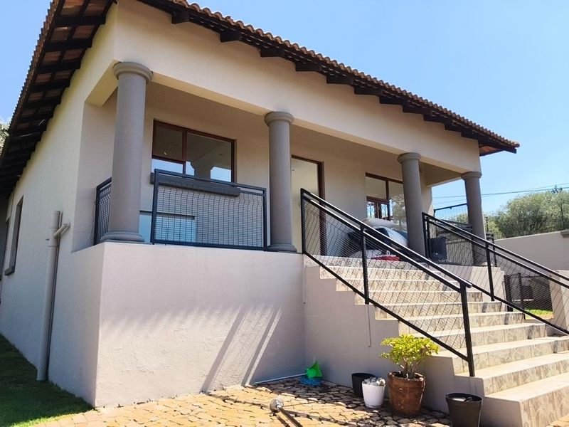 A raised rear exterior view featuring a covered patio with concrete columns, tiled staircase, and modern metal balustrades.