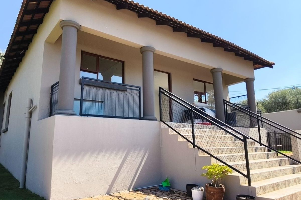 A raised rear exterior view featuring a covered patio with concrete columns, tiled staircase, and modern metal balustrades.