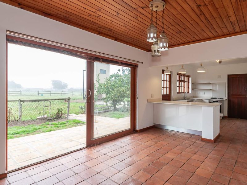Open plan living and kitchen area featuring terracotta flooring, a wooden ceiling, and large sliding doors opening to the garden.