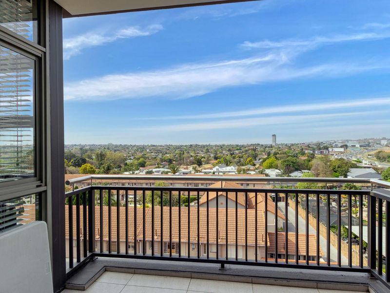 A spacious balcony featuring a metal balustrade and tiled flooring, offering expansive elevated views of the surrounding neighborhood and landscape.