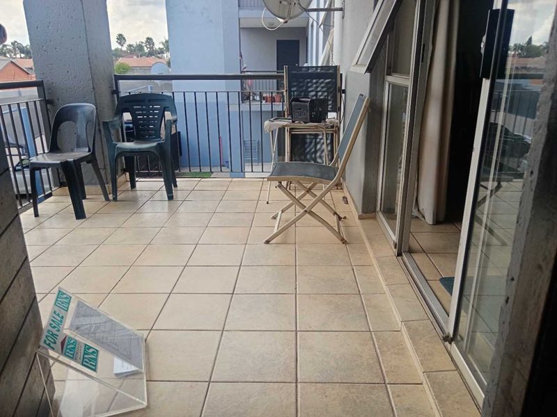 A covered balcony featuring tiled flooring and a metal balustrade, providing an outdoor space accessible via a sliding glass door.