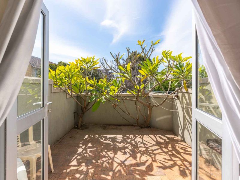 A private balcony featuring brick paving and a parapet wall, accessible through double french doors.