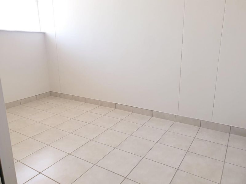 A clean, empty room featuring neutral tiled flooring and matching skirting, providing a blank canvas for interior design.